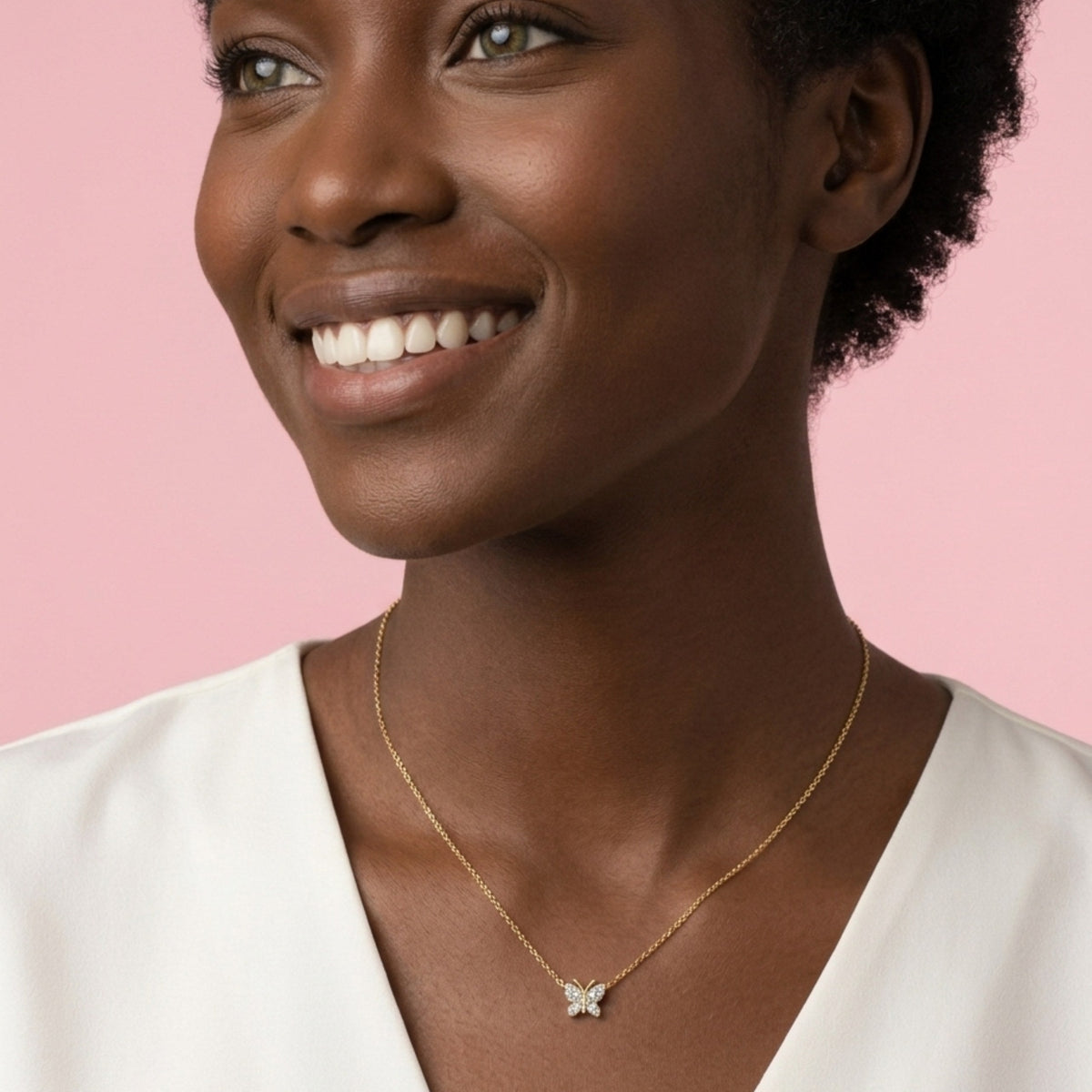 Woman wearing a gold necklace with a pink background