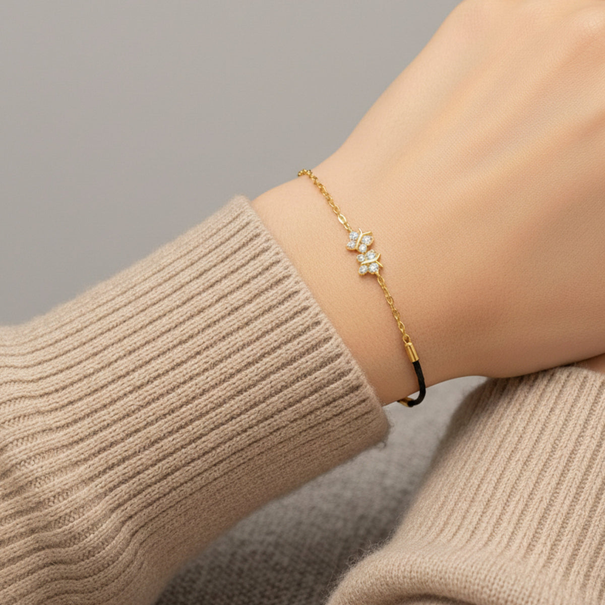 Gold bracelet with a star design on a wrist wearing a beige sweater.