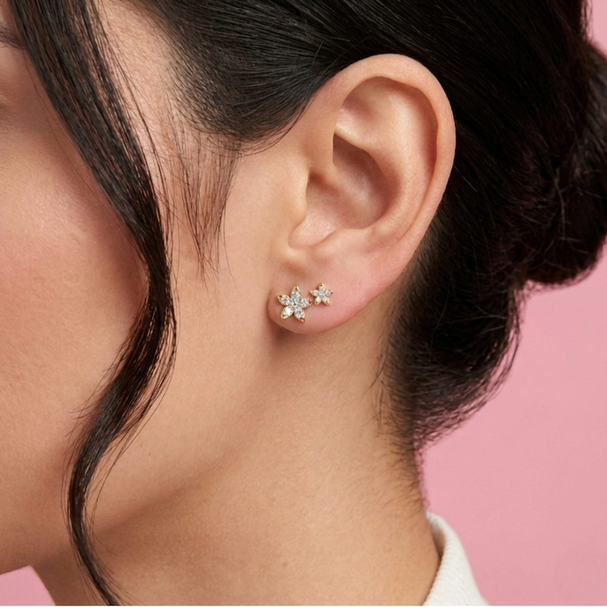 Close-up of an ear wearing a star-shaped earring with a pink background