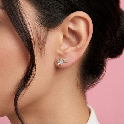 Close-up of an ear wearing a star-shaped earring with a pink background