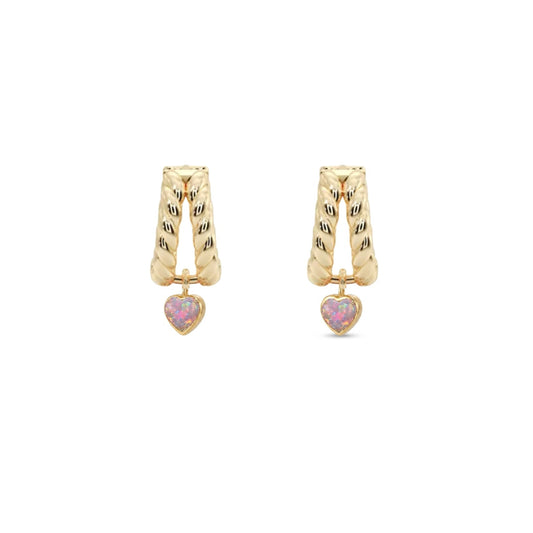 A pair of gold huggie hoop earrings with textured vertical bars and a small dangling pink heart charm, shown on a plain white background.