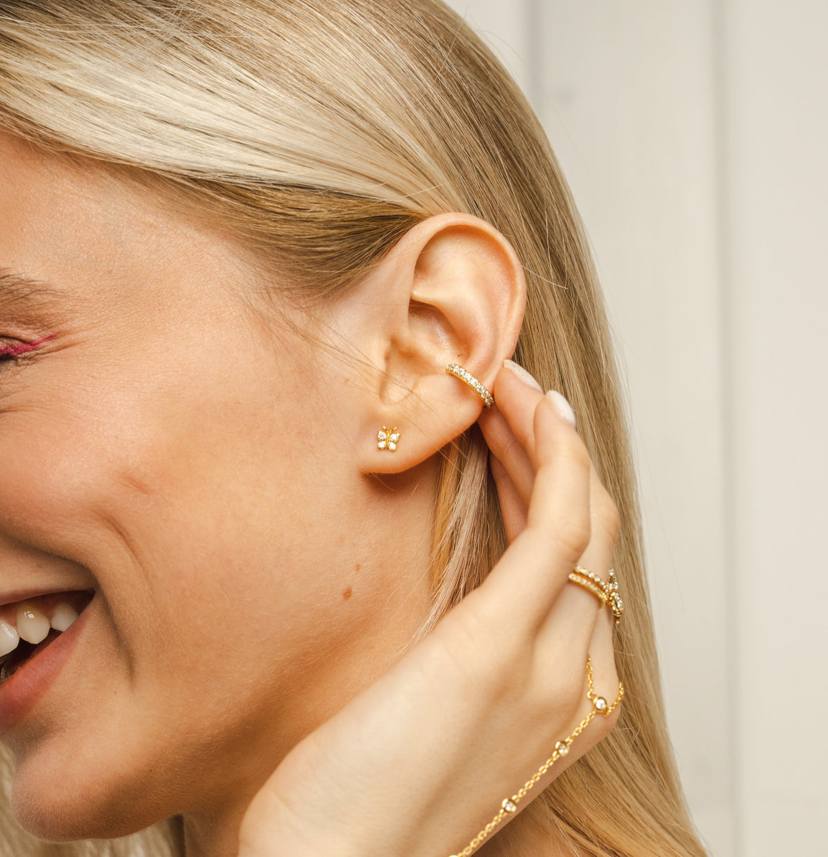 Lifestyle shot of the BLOOMTINE gold butterfly moissanite studs on a woman's ear. These 18k gold-over-silver earrings showcase the perfect scale for a dainty yet impactful look, highlighting the tarnish-resistant finish and high-brilliance stones against a soft-focus background