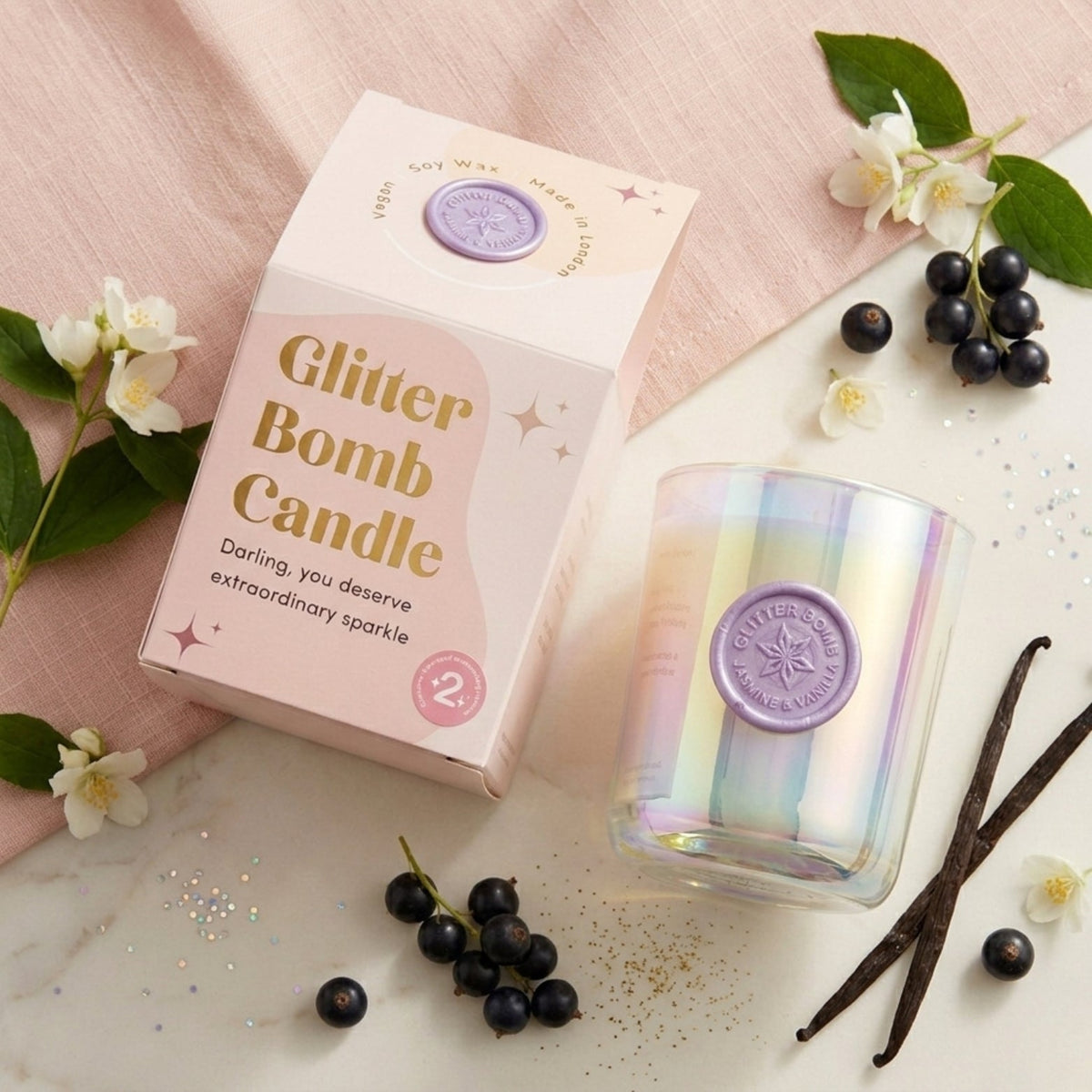 BLOOMTINE Glitter Bomb pink sparkle candle inside an opulent pink glass vessel. A luxury patchouli vanilla candle displaying a melted pool of shimmering pink soy wax