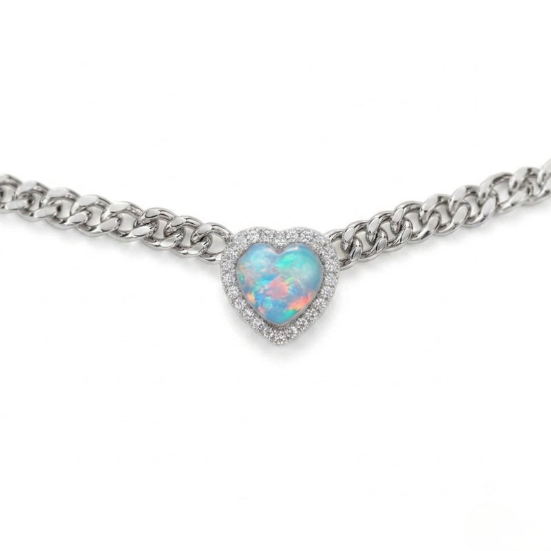 A silver-tone chain bracelet featuring a heart-shaped opal pendant with a halo of small clear stones, shown against a plain white background.