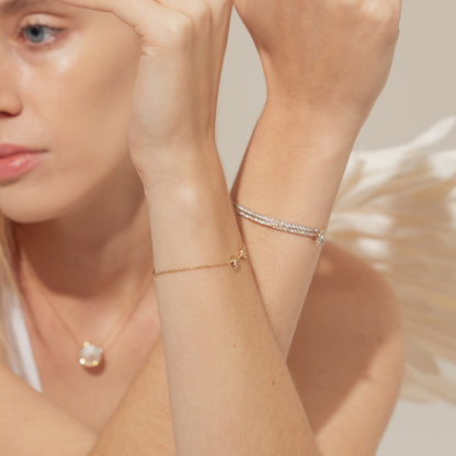 Close-up of a woman's arm wearing a gold bracelet with a blurred background. Bloomtine-Illuminess-14K-solid-rose-gold-diamond-bar-bracelet. A professional-hero-shot of a-luxury-fine-jewelry-bracelet featuring 21-premium-VVS-lab-grown-diamonds set in a-solid-rose-gold-bar. Displayed-on-a-clean-white-background, this-piece highlights the-mirror-like-polish and exceptional-brilliance of the-sustainable-diamonds, representing-modern-sophistication and ethical-luxury